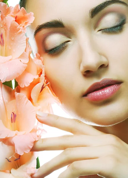 Visage frais avec des fleurs de gladiole dans ses mains — Photo