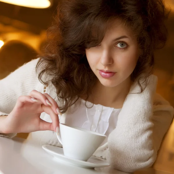 Молода жінка насолоджується лате кавою в кафе — стокове фото