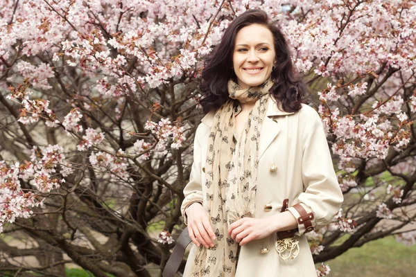 Heureuse jeune femme dans le jardin de fleurs de printemps — Photo