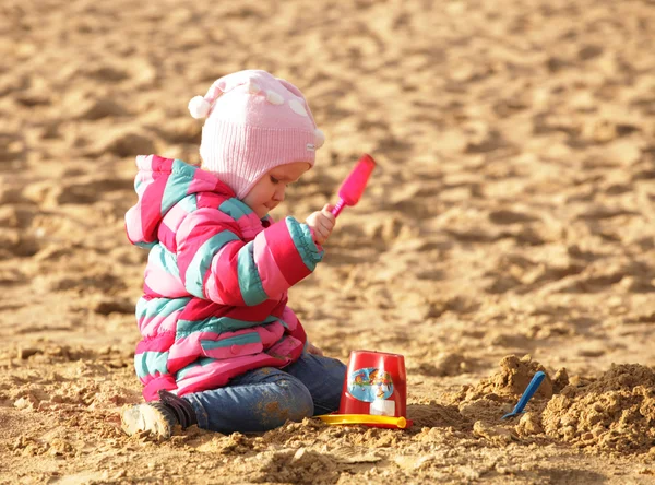 Mädchen spielt mit Sand am Herbststrand — Stockfoto