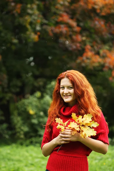 Junge Frau mit Herbstlaub im Park — Stockfoto