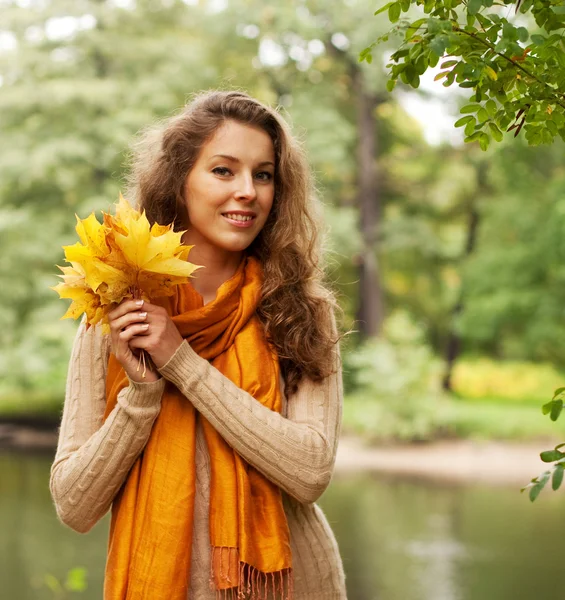 Giovane donna con foglie autunnali nel parco — Foto Stock