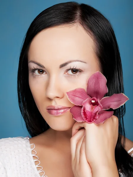 Vrouw met orchidee bloem op blauwe achtergrond — Stockfoto