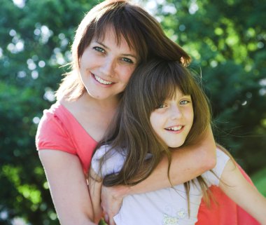 Anne ve kızı açık gülümseyen.