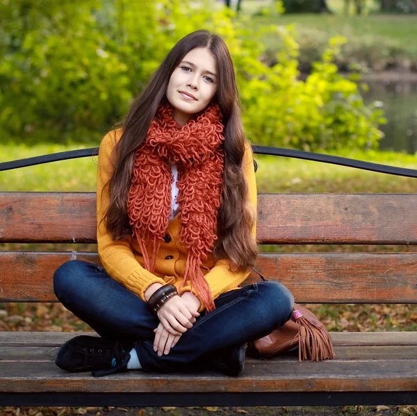 Meisje op bank in herfstpark — Stockfoto