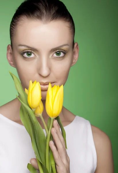 Mulher com flores amarelas no fundo verde — Fotografia de Stock