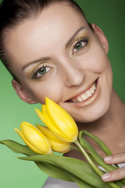 Mulher com flores amarelas no fundo verde — Fotografia de Stock