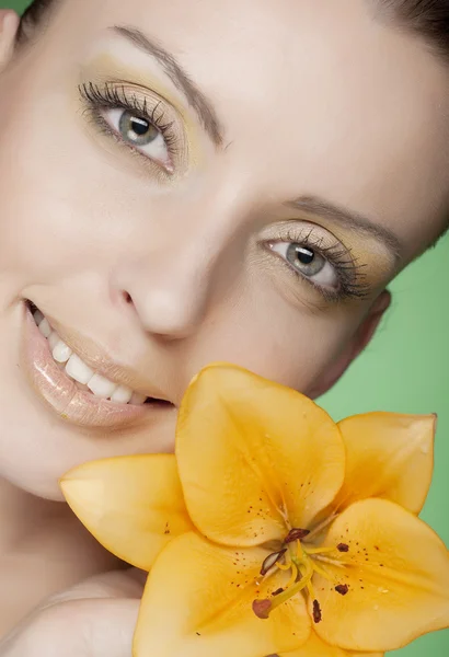 緑の背景に黄色の花を持つ女性 — ストック写真