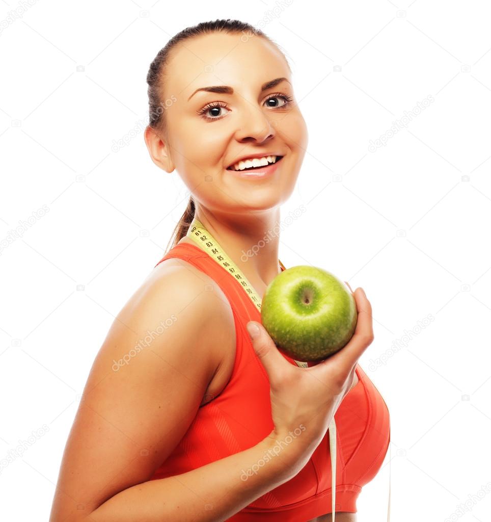 Young cheerful woman in sports wear with apple