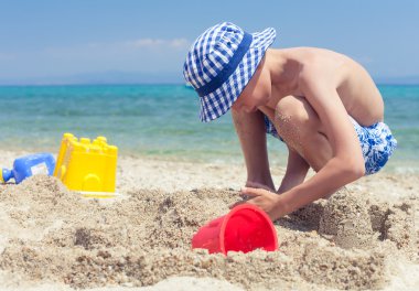 Kumdan kale inşa kumsalda oynarken bir panama ile komik küçük çocuk