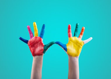 Yeşil arka plan üzerinde renkli parmak boya ile boyanmış çocuğun elleri