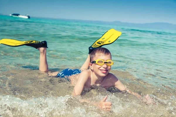 Šťastné dítě potápěč v swimware ležet na pláži, v moři s úsměvem — Stock fotografie