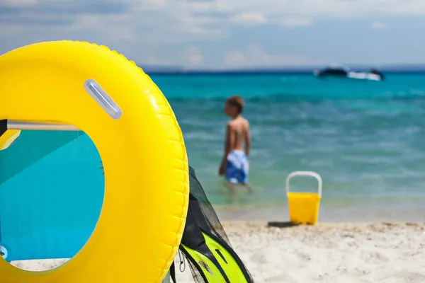 Strand accessoires en stoel op strand en kind spelen rond. zomer vakantie concept. — Stockfoto