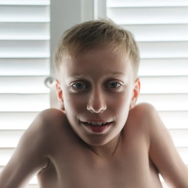 Funny little boy on summer vacation in front of a window.  Candid closeup portrait. — Stock Photo, Image