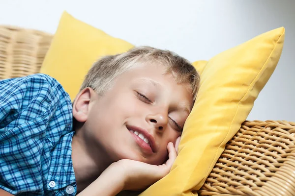 Bellissimo bambino che dorme tranquillamente su un divano di vimini — Foto Stock