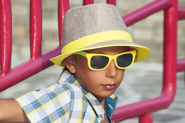 Krásné legrační dítě s elegantní žlutý sluneční brýle a čepici pózuje venku v létě — Stock fotografie