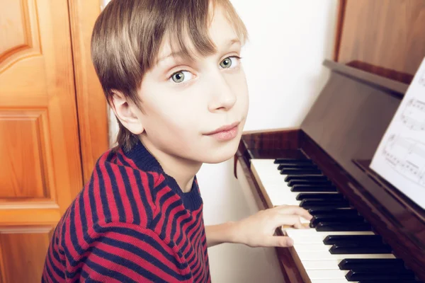 아름 다운 작은 아이 카메라를 보고 피아노 연주 — 스톡 사진
