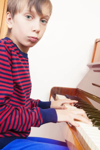 Piękne małe dziecko gra fortepian patrząc na kamery — Zdjęcie stockowe
