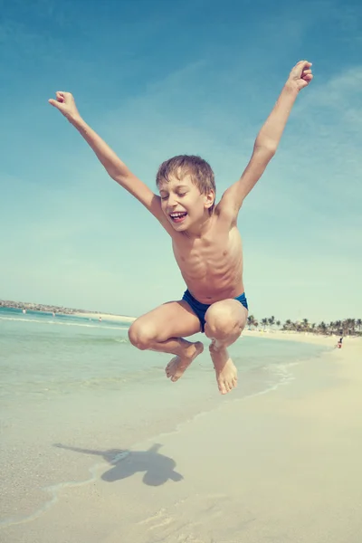 Grappige kindje springen op het strand en lachen. — Stockfoto