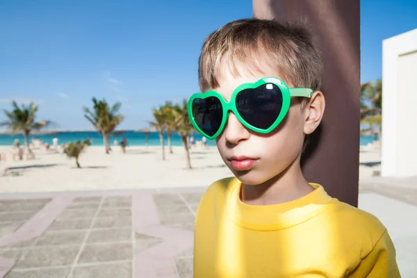 Piękne dziecko sobie śmieszne stylowe okulary stojąc na plaży — Zdjęcie stockowe