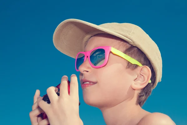 Mooi kind draagt stijlvolle zonnebril vasthouden van camera — Stockfoto