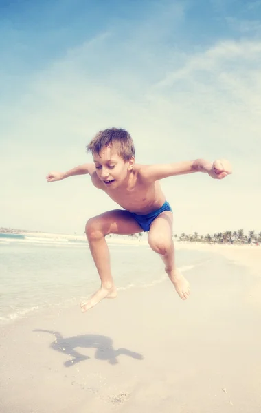 Schattig grappige klein kind springen op het strand — Stockfoto