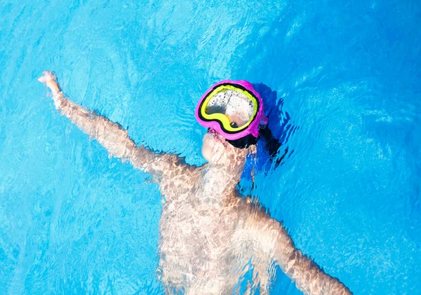 Niño con una colorida máscara de buceo nadando en una piscina —  Fotos de Stock
