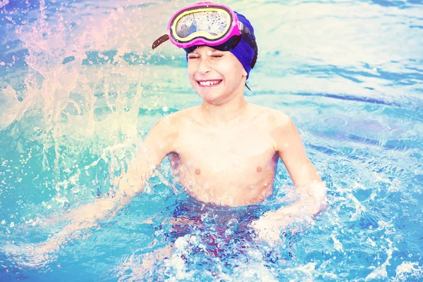 Niño con una colorida máscara de natación salpicando agua en una piscina al aire libre —  Fotos de Stock