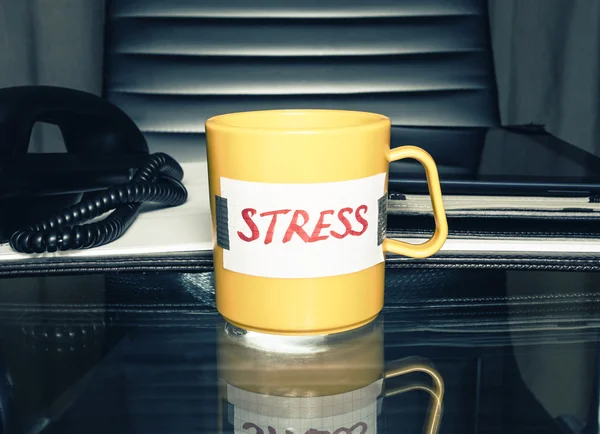 Kaffekopp med meddelandet "stress" på en office-tabell med business tillbehör. stress och depression koncept. — Stockfoto