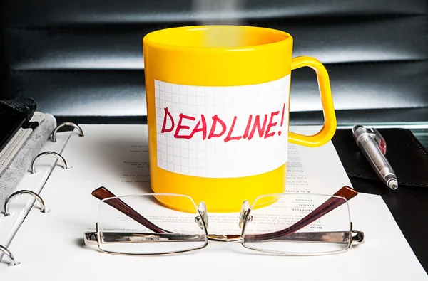 Creatieve bedrijfsconcept. een koffiekopje met een boodschap "deadline" op office tabel — Stockfoto