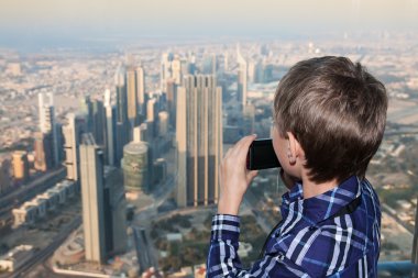 küçük çocuk bir kamera çekimi fotoğraf tutarak yukarıda büyük bir şehir, izlerken