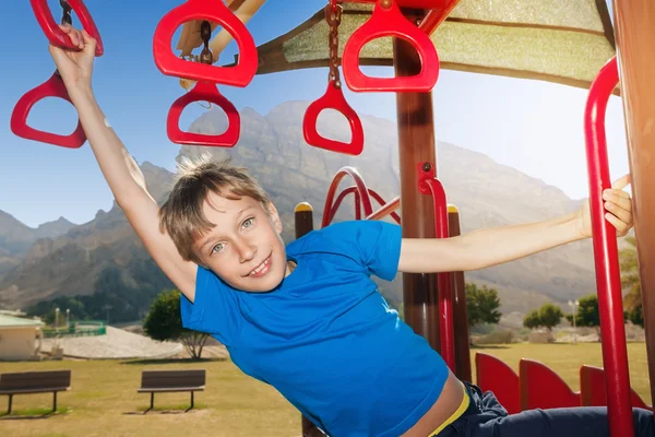 Hermoso niño alegre jugando en un patio de verano soleado con un columpio —  Fotos de Stock
