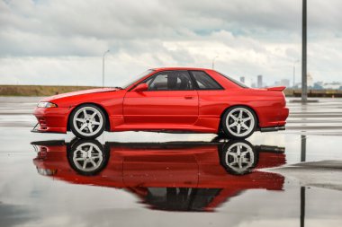 Nissan skyline R 32 kırmızı renk bir ıslak yolda