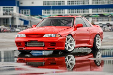 Nissan skyline R 32 kırmızı renk bir ıslak yolda