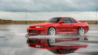 Nissan skyline R 32 kırmızı renk bir ıslak yolda