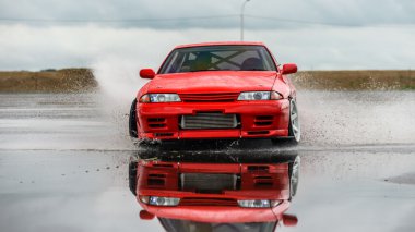 Nissan skyline R 32 kırmızı renk bir ıslak yolda
