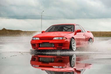 Nissan skyline R 32 kırmızı renk bir ıslak yolda