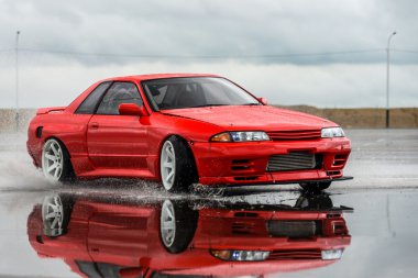 Nissan skyline R 32 kırmızı renk bir ıslak yolda