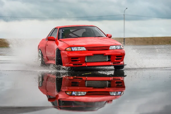 Nissan skyline R 32 kırmızı renk bir ıslak yolda