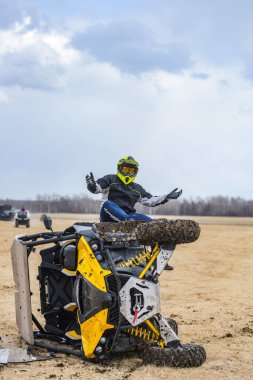 ATV UTV devrildi, sürücü bozuk arazi aracının yanında oturuyor.
