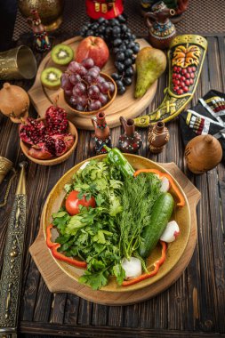 Kırmızı domatesli taze yeşil salata yaprakları, salatalık ve turp beyaz kasede ahşap arka planda.