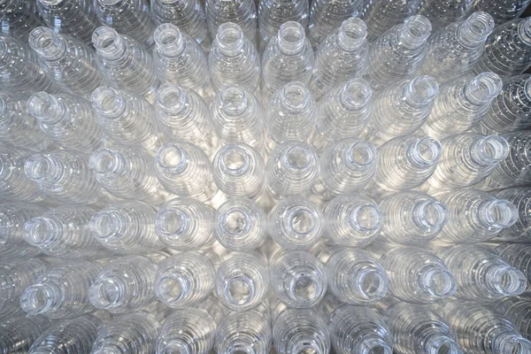 The various type of plastic bottle product and preform material with injection mold background. Drinking container manufacturing processing.