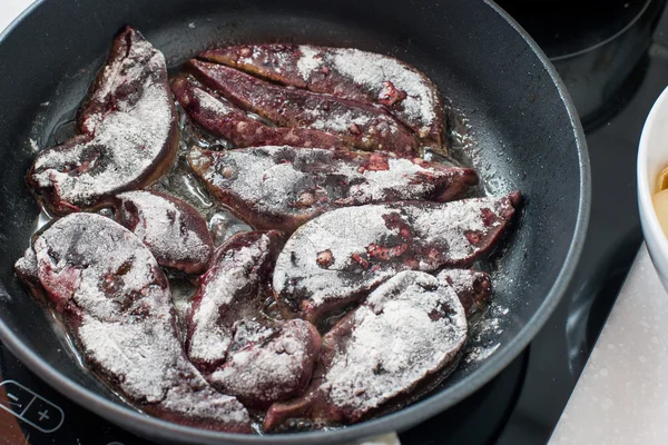 Приготування яловичої печінки, покритої борошном на сковороді . — стокове фото