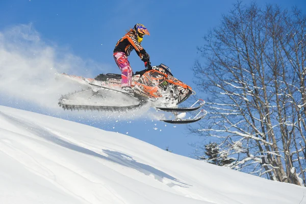 Atleta en una moto de nieve moviéndose en las montañas — Foto de Stock