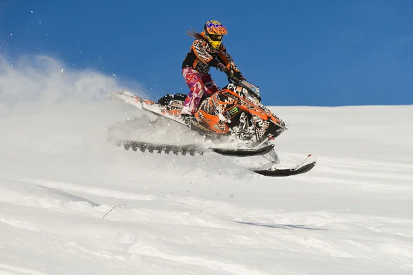 Atleta en una moto de nieve moviéndose en las montañas — Foto de Stock