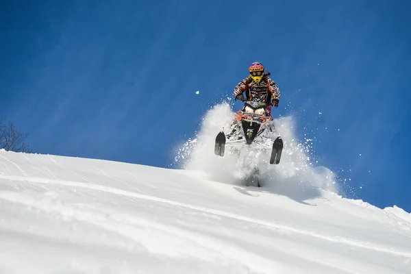 Atleta em um snowmobile que se move nas montanhas — Fotografia de Stock