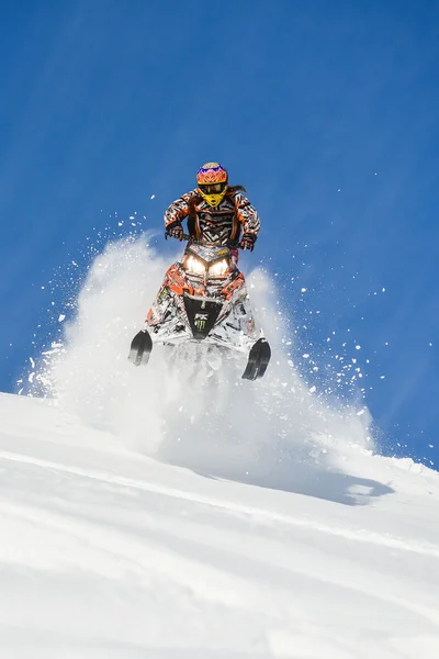 Atleta en una moto de nieve moviéndose en las montañas —  Fotos de Stock