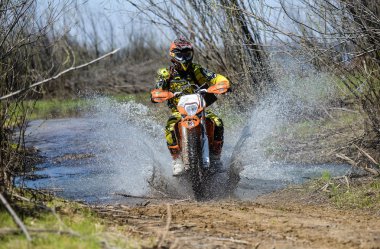 Enduro motorcycle rides through the mud with a big splash