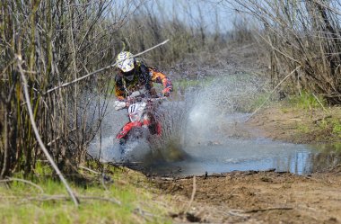 Enduro motorcycle rides through the mud with a big splash