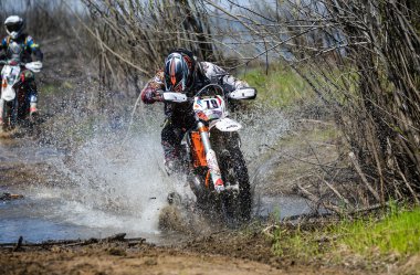 Enduro motorcycle rides through the mud with a big splash